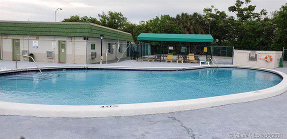 Outdoor swimming pool area with a fence and green-roofed structure.