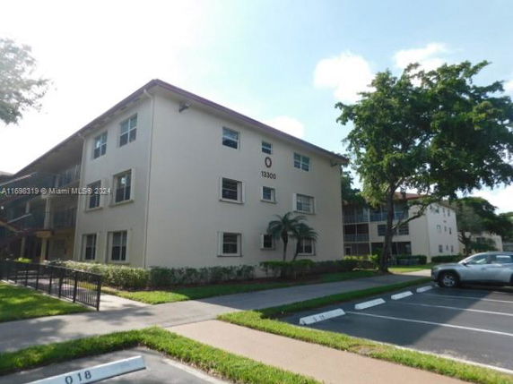 Front view of a three-story apartment building with parking area.