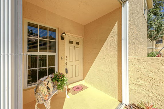 Front view of a house entrance with a door and window, decorative bench, and potted plant.