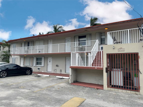 Front view of a two-story building with a balcony and parking area.