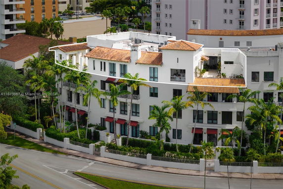 Front view of a multi-story residential building with red-tiled roofs and multiple balconies.