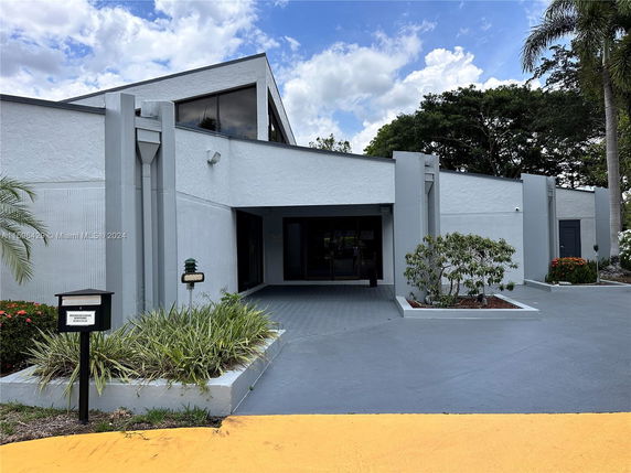 Front view of a modern single-story building with a flat roof and a covered entrance.