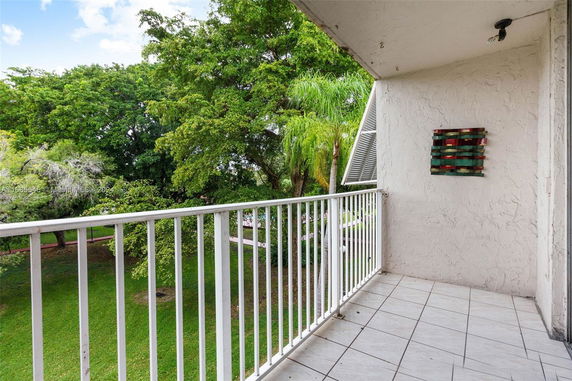 Balcony with white railing overlooking a lush green garden.