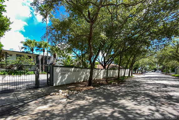 Front view of a building with a gated entrance and surrounding trees.