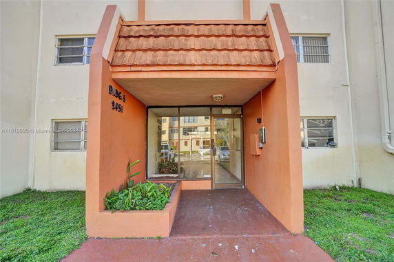 Front view of a building entrance with a small sidewalk and planter.