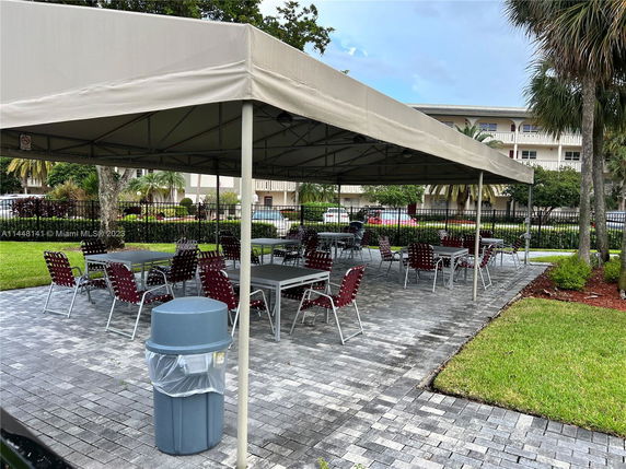 Outdoor seating area with tables and chairs under a large canopy.