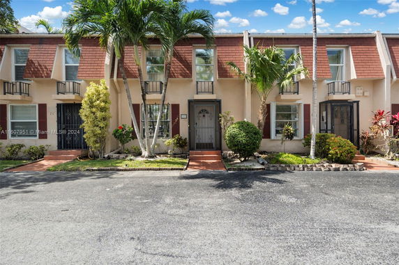 Front view of a multi-story townhouse with trees and plants.