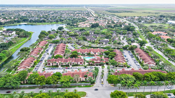 Aerial view of a residential area with rows of houses, parking spaces, and surrounding greenery.