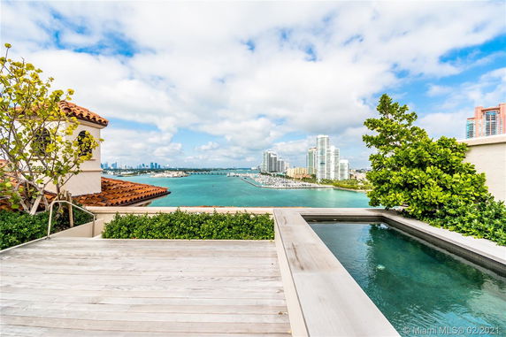 Rooftop area with a pool overlooking a waterway and city skyline.