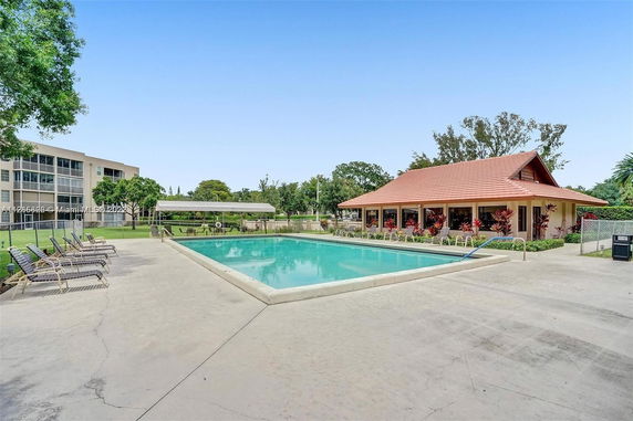 Outdoor swimming pool area with adjacent building and seating.