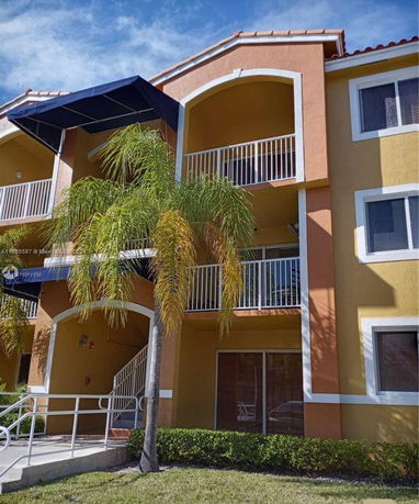 Front view of a multi-story apartment building with balconies and an awning.