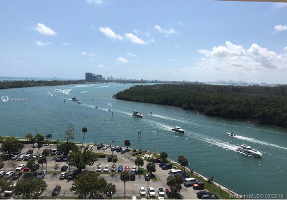 Panoramic view of a river with several boats and distant city skyline.