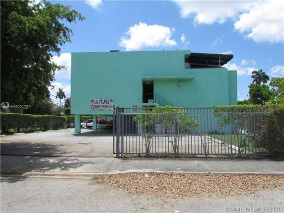 Front view of a two-story condominium building with a flat roof and a gated entrance.