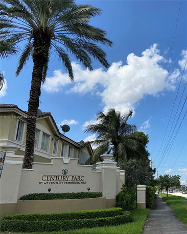 Front view of a building with palm trees and a sign reading 'Century Parc'.