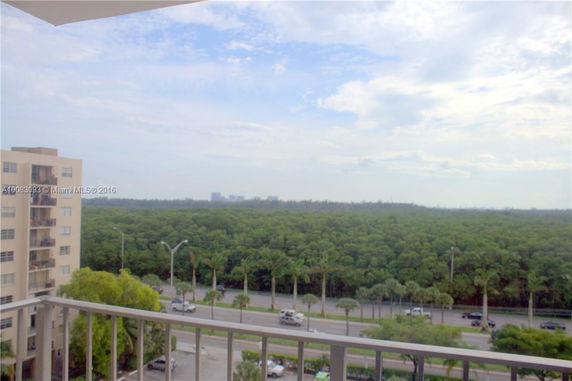 View from a balcony overlooking a forest and road.