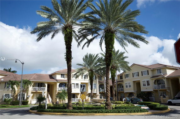 Front view of a multi-story residential building with balconies and tiled roof.