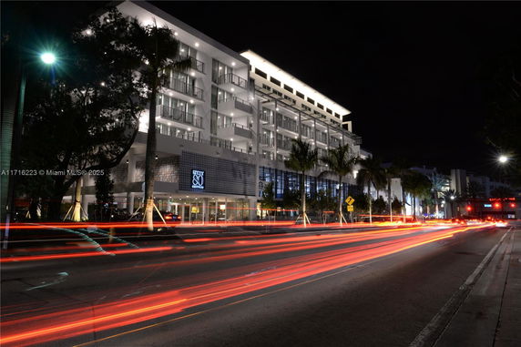 Front view of a multi-story building with balconies at night.