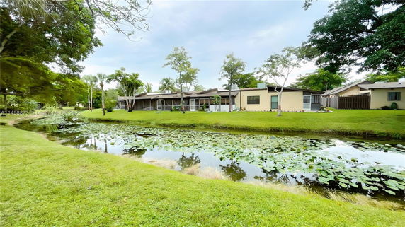 View of buildings with a pond in the foreground and trees surrounding the area.