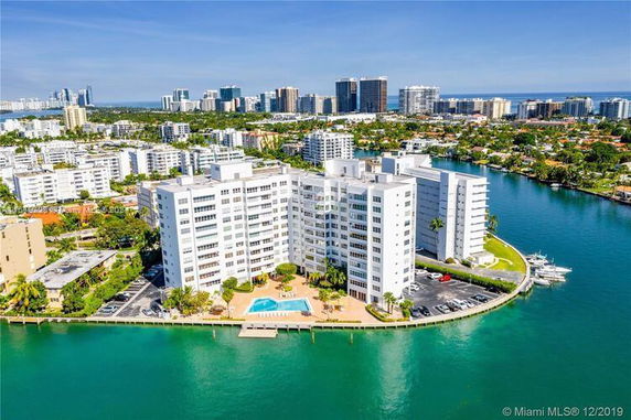Aerial view of a multi-story waterfront apartment building with swimming pool.
