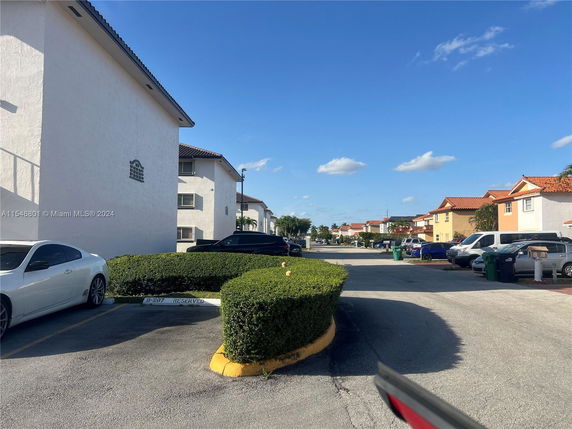 Outdoor parking area of a residential complex with cars parked.