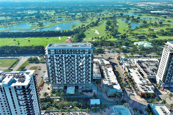 Aerial view of a rooftop on a high-rise building with adjacent structures and a golf course in the background.