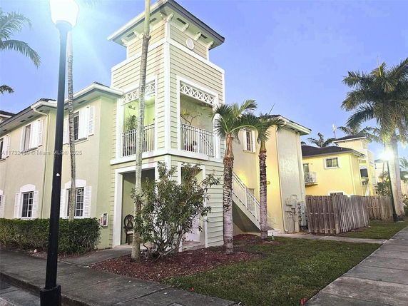 Front view of a two-story house with a balcony and exterior staircase.