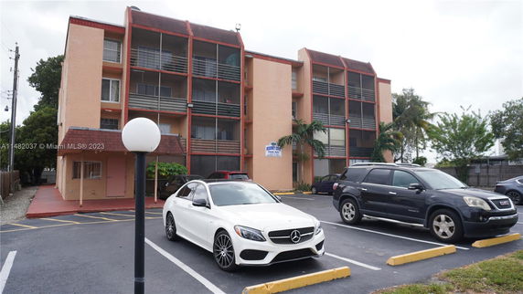 Front view of a multi-story residential building with parking area.