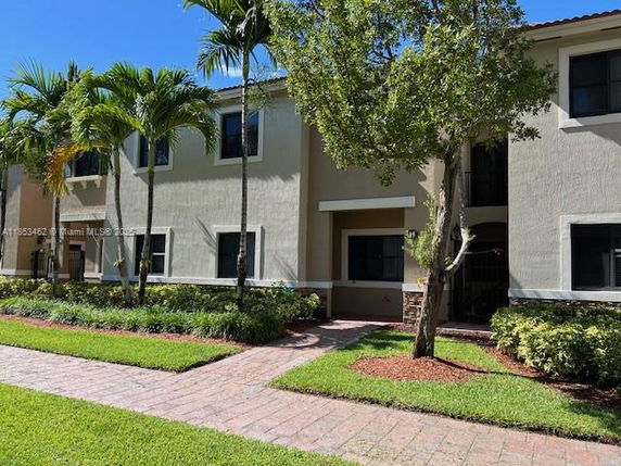 Front view of a two-story residential building with palm trees and a walkway.