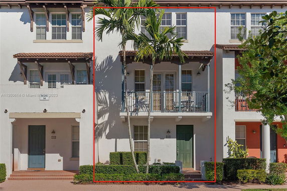 Front view of a two-story townhouse with a small balcony and green door.