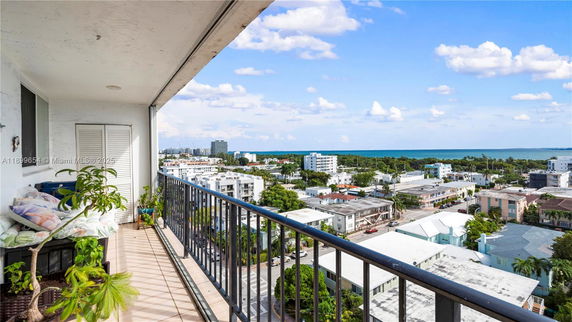 View from a high-rise balcony overlooking a coastal cityscape with ocean in the distance.