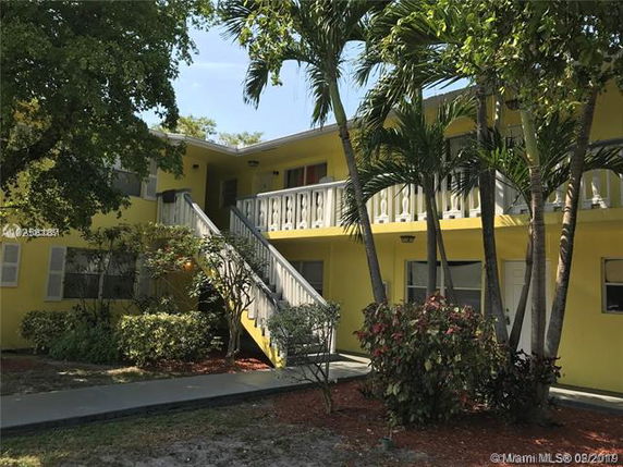 Front view of a two-story yellow building with exterior stairs and balcony.