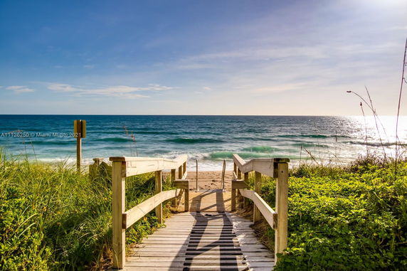 Wooden walkway leading to a sandy beach with ocean view.