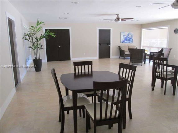 Indoor recreation area with tables and chairs, featuring light-colored walls and a ceiling fan.