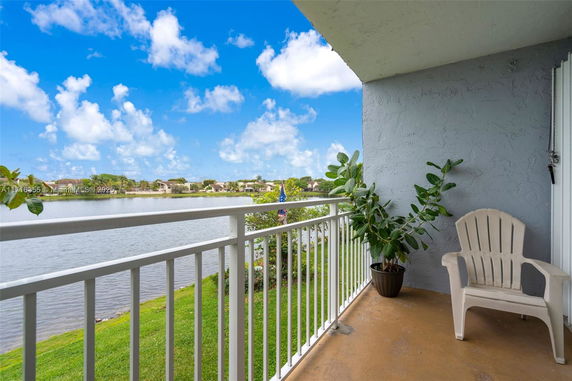 View from a balcony overlooking a lake and distant houses.