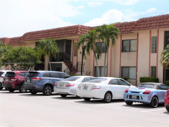 Front view of a two-story apartment building with adjacent parking area.