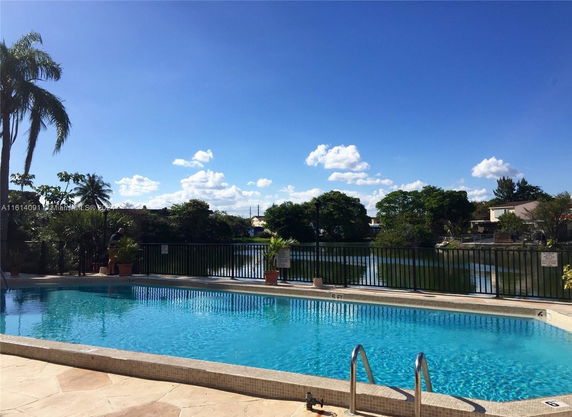 Outdoor swimming pool with a view of surrounding trees and a lake.