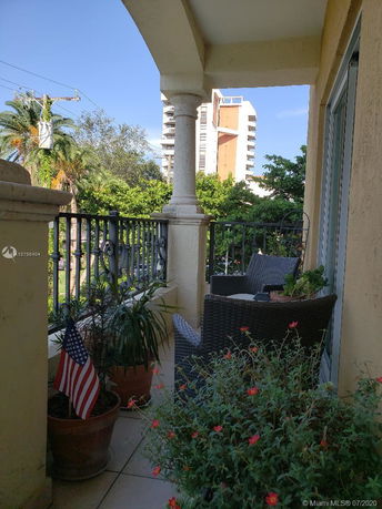 Balcony view with outdoor furniture, railing, and a glimpse of nearby tall buildings.