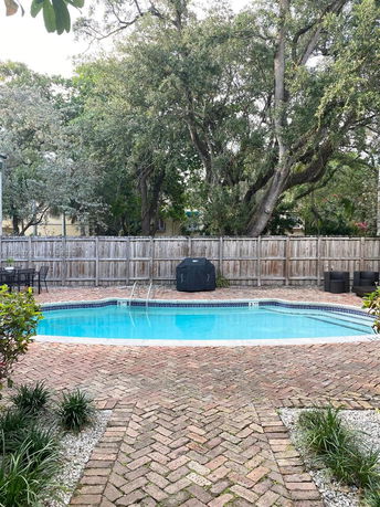 View of a swimming pool surrounded by trees and a wooden fence.