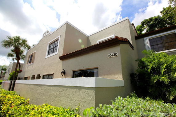 Front view of a multi-story house with a stucco exterior and tiled roof.
