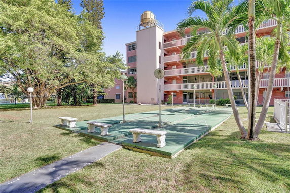 Outdoor view of a multi-story building with balconies and an adjacent recreational area with benches.