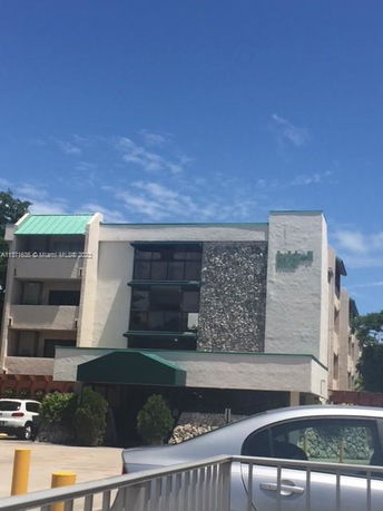 Front view of a multi-story building with a green awning and stone facade.