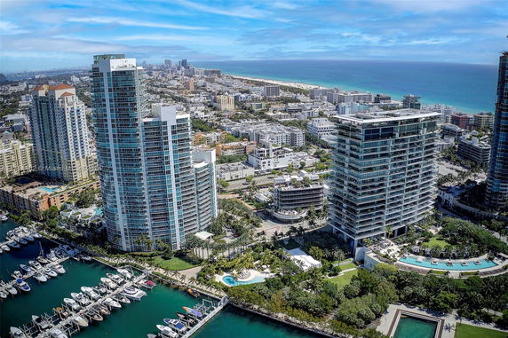 Panoramic view of high-rise buildings near the waterfront with a cityscape and ocean in the background.