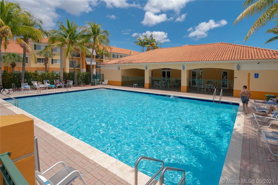 Outdoor swimming pool area with a building featuring a tiled roof.