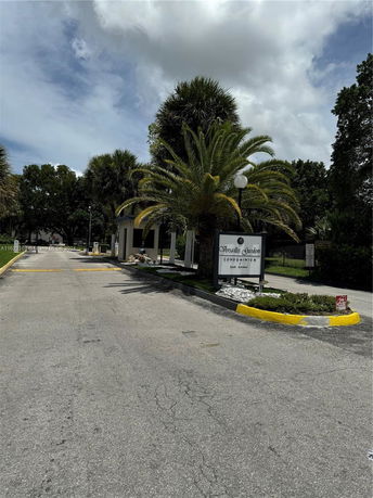Driveway entrance to a condominium complex with a sign.