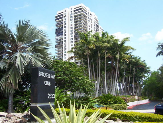 Front view of a multi-story condominium building with surrounding palm trees.