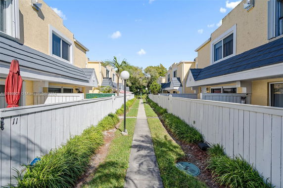 View of a row of townhouses with white fences and a pathway in between.