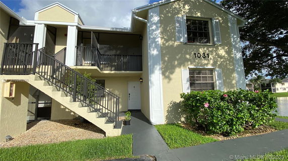 Front view of a two-story building with exterior staircases and labeled entrance.