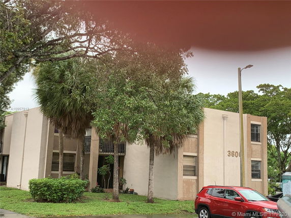 Front view of a two-story beige building with multiple windows and a car parked in front.
