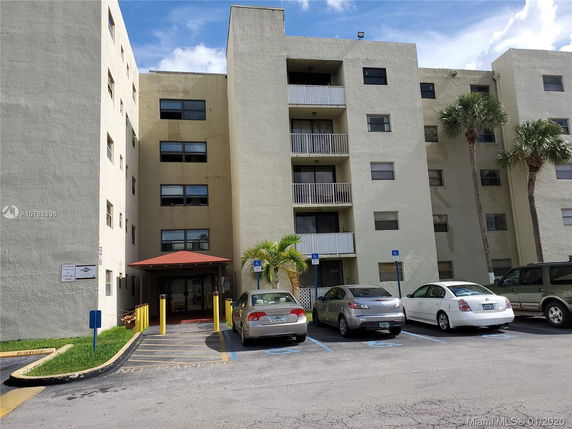 Front view of a multi-story apartment building with several balconies and an entrance canopy.