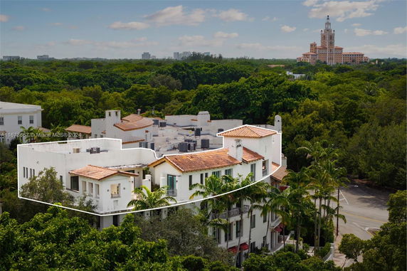 Aerial view of a multi-story building with a red-tiled roof surrounded by trees.
